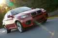 BMW X6 M rouge 3/4 avant droit travelling penché