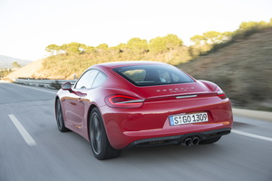 Porsche Cayman S II rouge vue de 3/4 arrière gauche en travelling