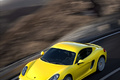 Porsche Cayman S jaune 3/4 avant gauche travelling vue de haut debout